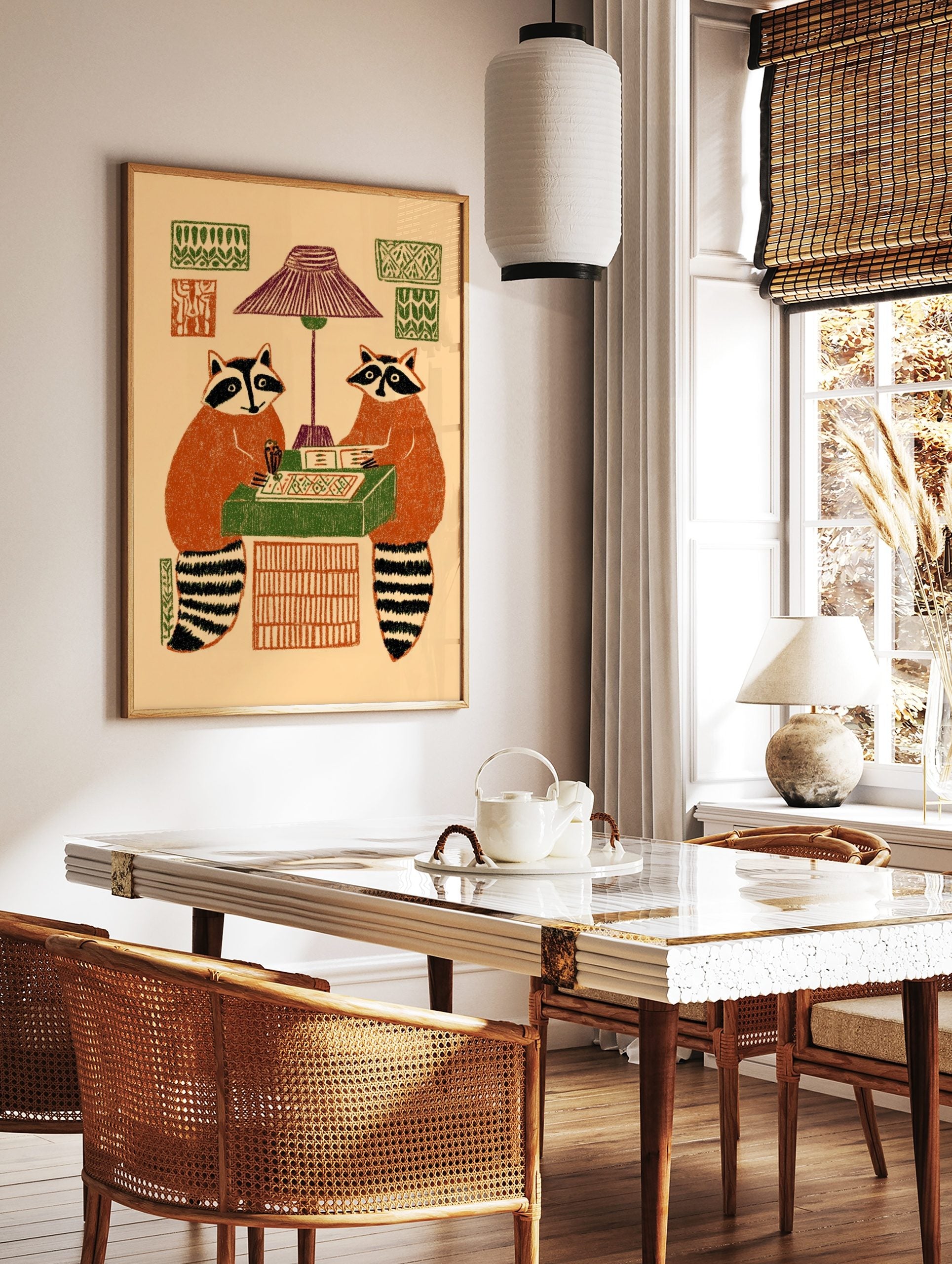 Illustrative print of two raccoons playing a board game under a lamp, with patterned wall decor, in a styled room mockup