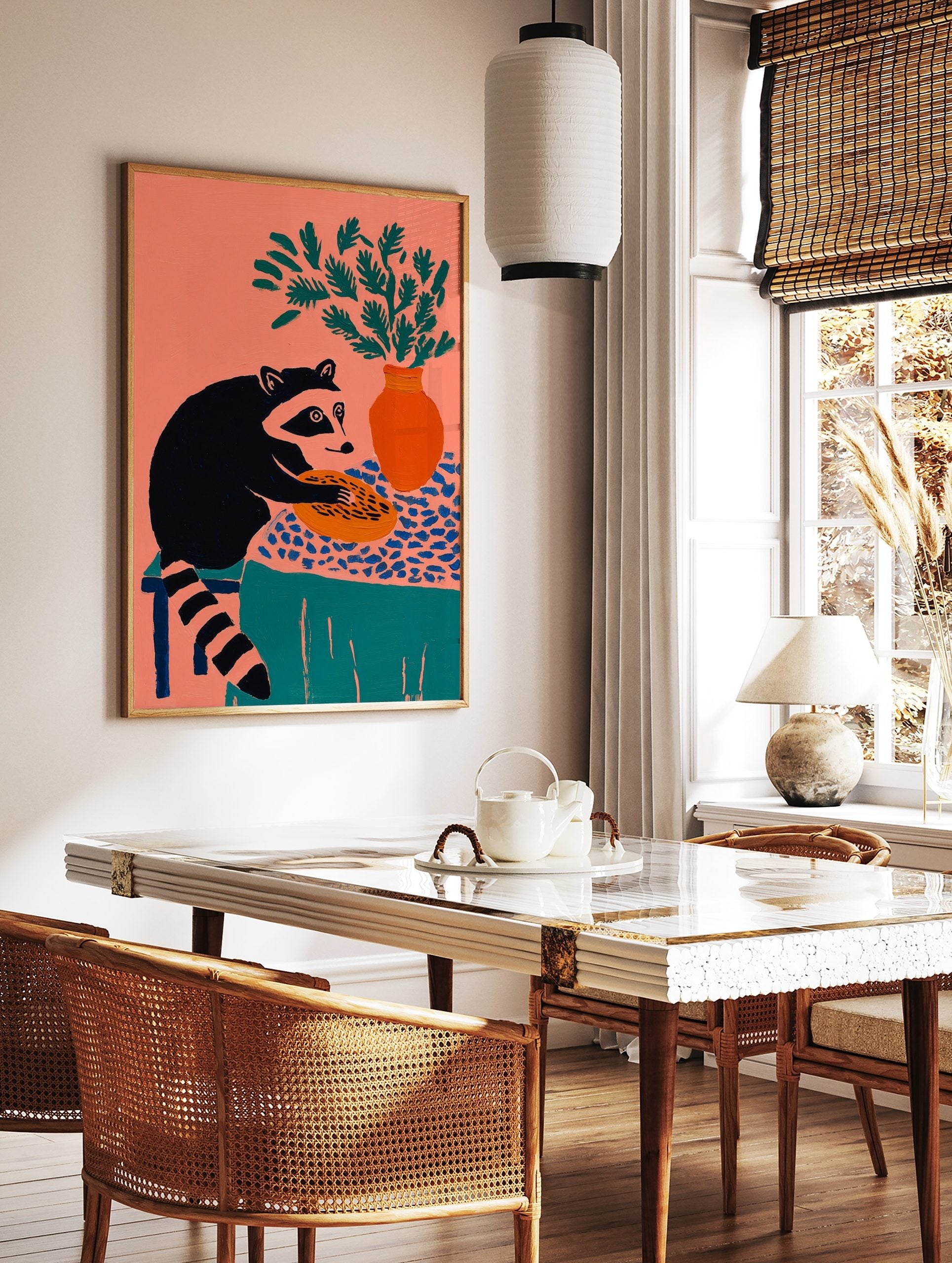 Illustrative raccoon holding a pie on a patterned tablecloth with a vase of green foliage, coral, in a styled room mockup