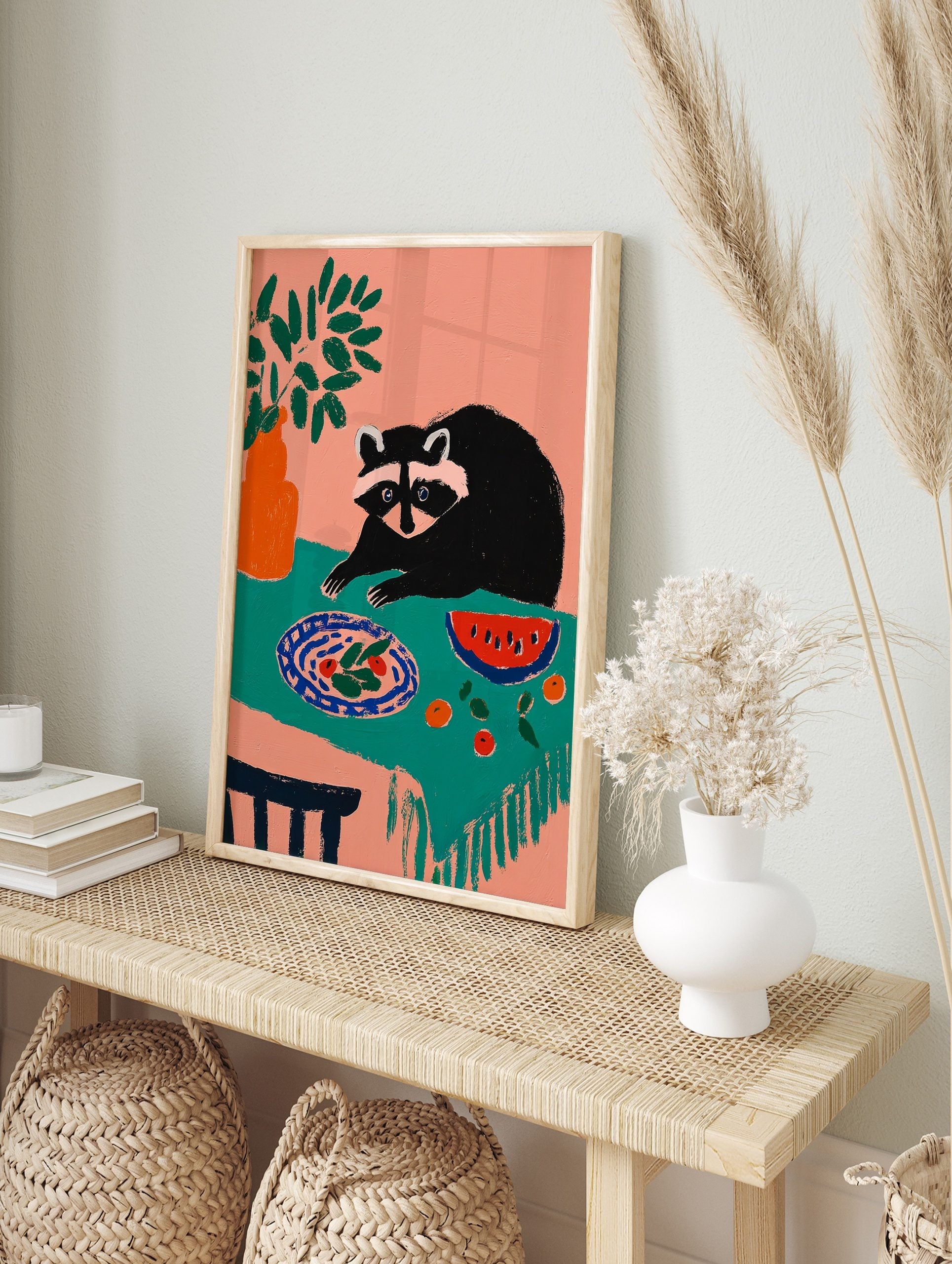 Illustrative art print of a raccoon looking at a plate of food and watermelon on a teal, in an alternate framed mockup