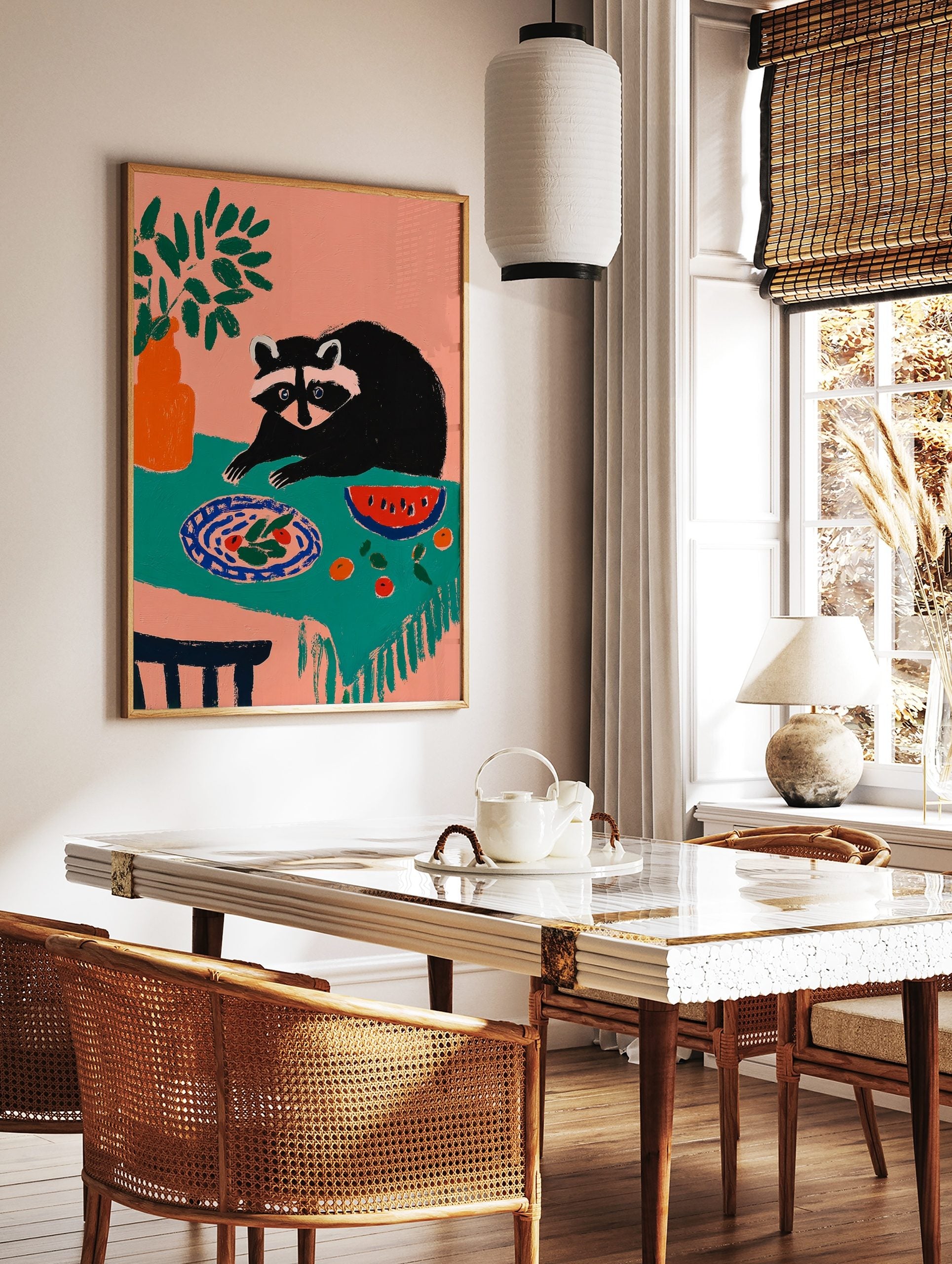 Illustrative art print of a raccoon looking at a plate of food and watermelon on a teal tablecloth, in a styled room mockup
