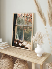 Watercolor painting of a rainy window with a steaming mug and open book on a wooden sill, in an alternate framed mockup
