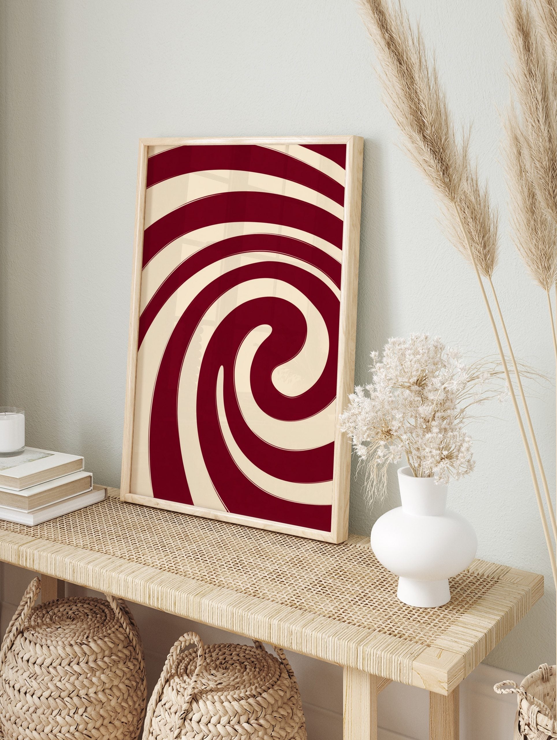 Abstract red and cream spiral wall art with bold, swirling lines and a hypnotic composition, in an alternate framed mockup