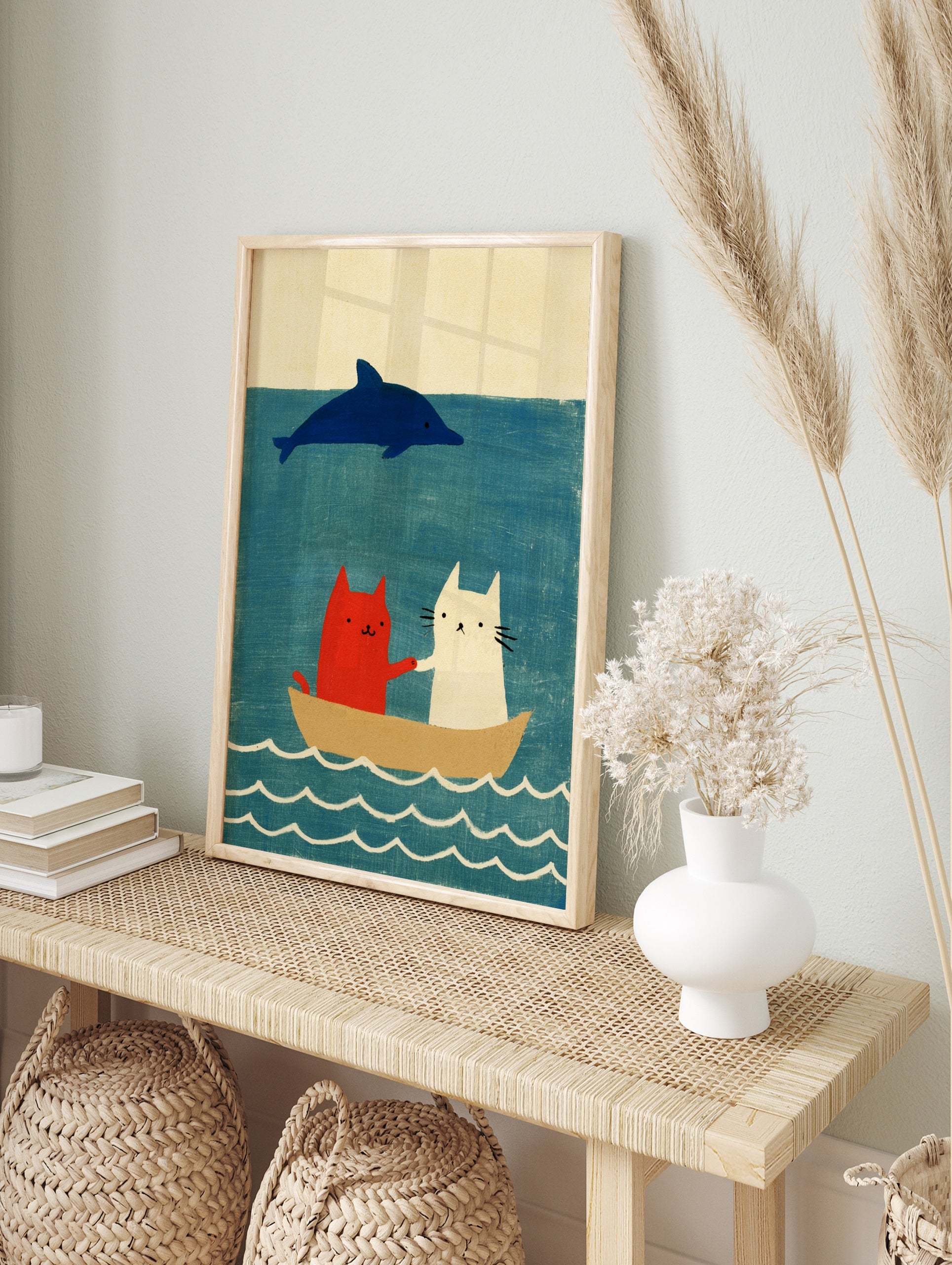 Red and white cat illustration with a blue dolphin in a boat on a blue sea, in an alternate framed mockup