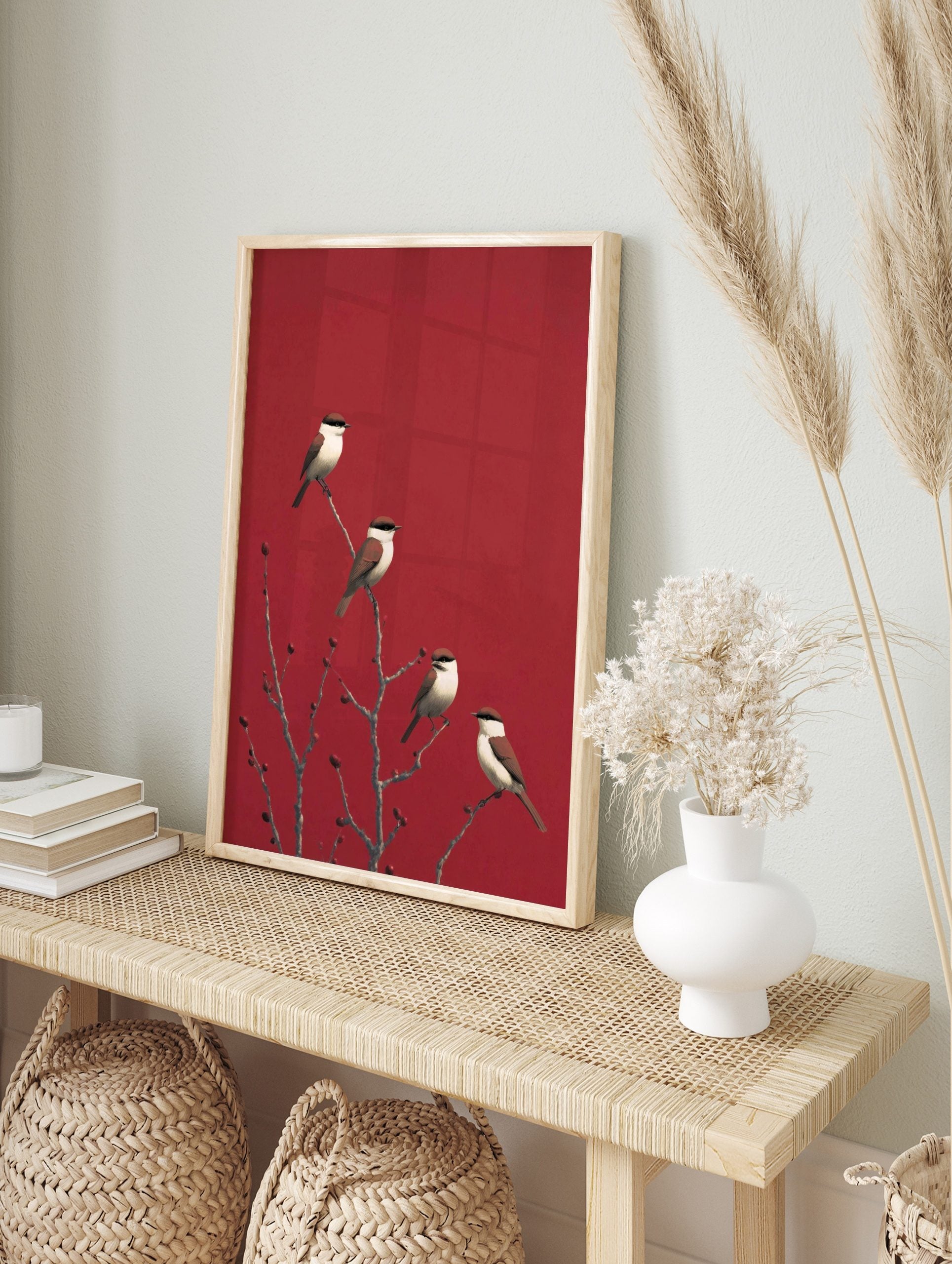 Four red-backed shrike birds on bare branches with red berries against a striking red, in an alternate framed mockup