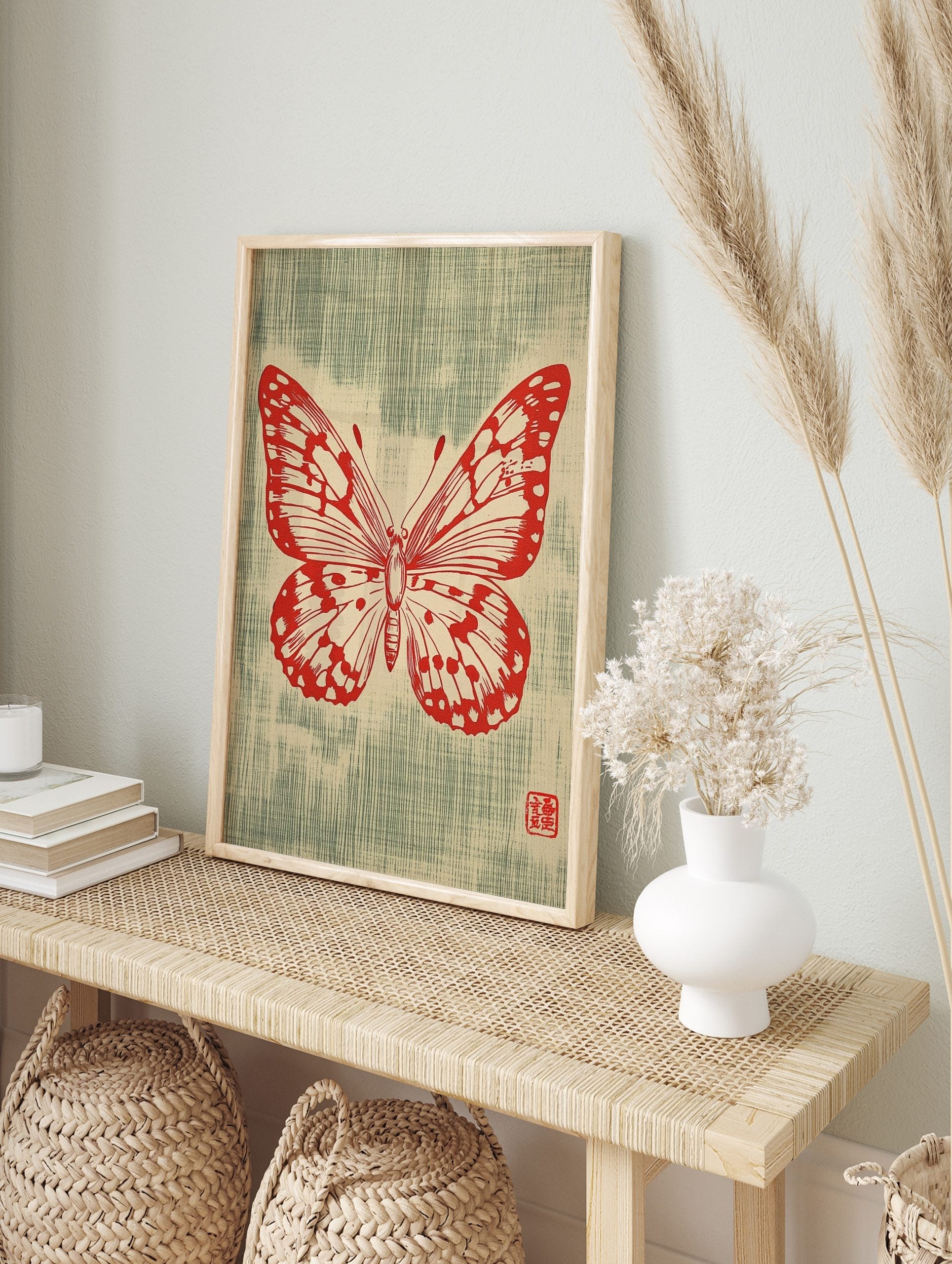 Red butterfly illustration with detailed wings and antennae on a textured greenish-blue, in an alternate framed mockup