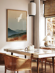 Red-crowned crane flying over misty blue mountains and autumn reeds in a Japanese-style art print, in a styled room mockup