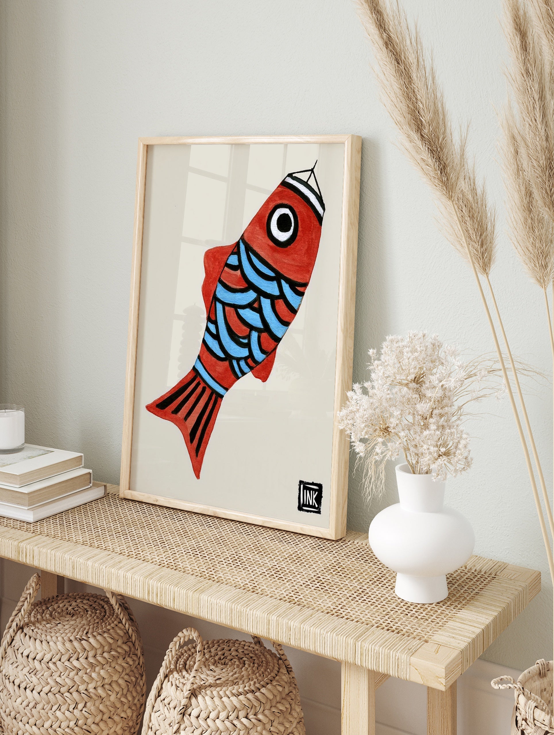 Illustrative red fish wall art with blue scales and graphic black details on a light, in an alternate framed mockup