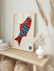 Illustrative red fish wall art with blue scales and graphic black details on a light, in an alternate framed mockup