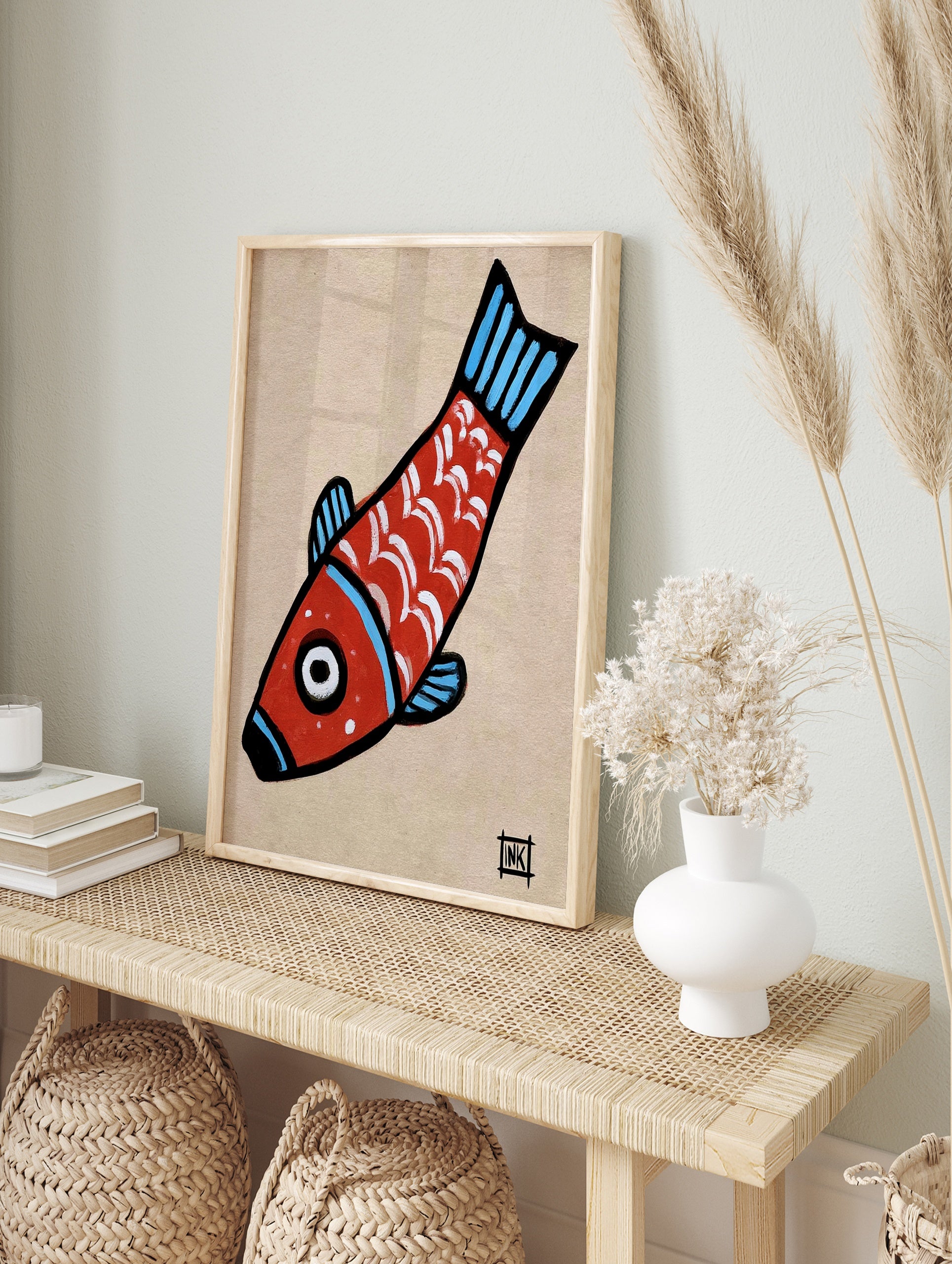 Stylised red fish illustration with white scales and blue fins on a tan paper background, in an alternate framed mockup