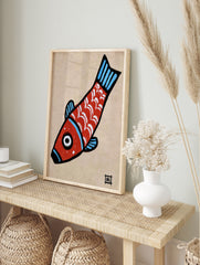 Stylised red fish illustration with white scales and blue fins on a tan paper background, in an alternate framed mockup