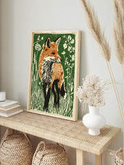 Illustrative red fox standing in green grass and white wildflowers, linocut style art print, in an alternate framed mockup
