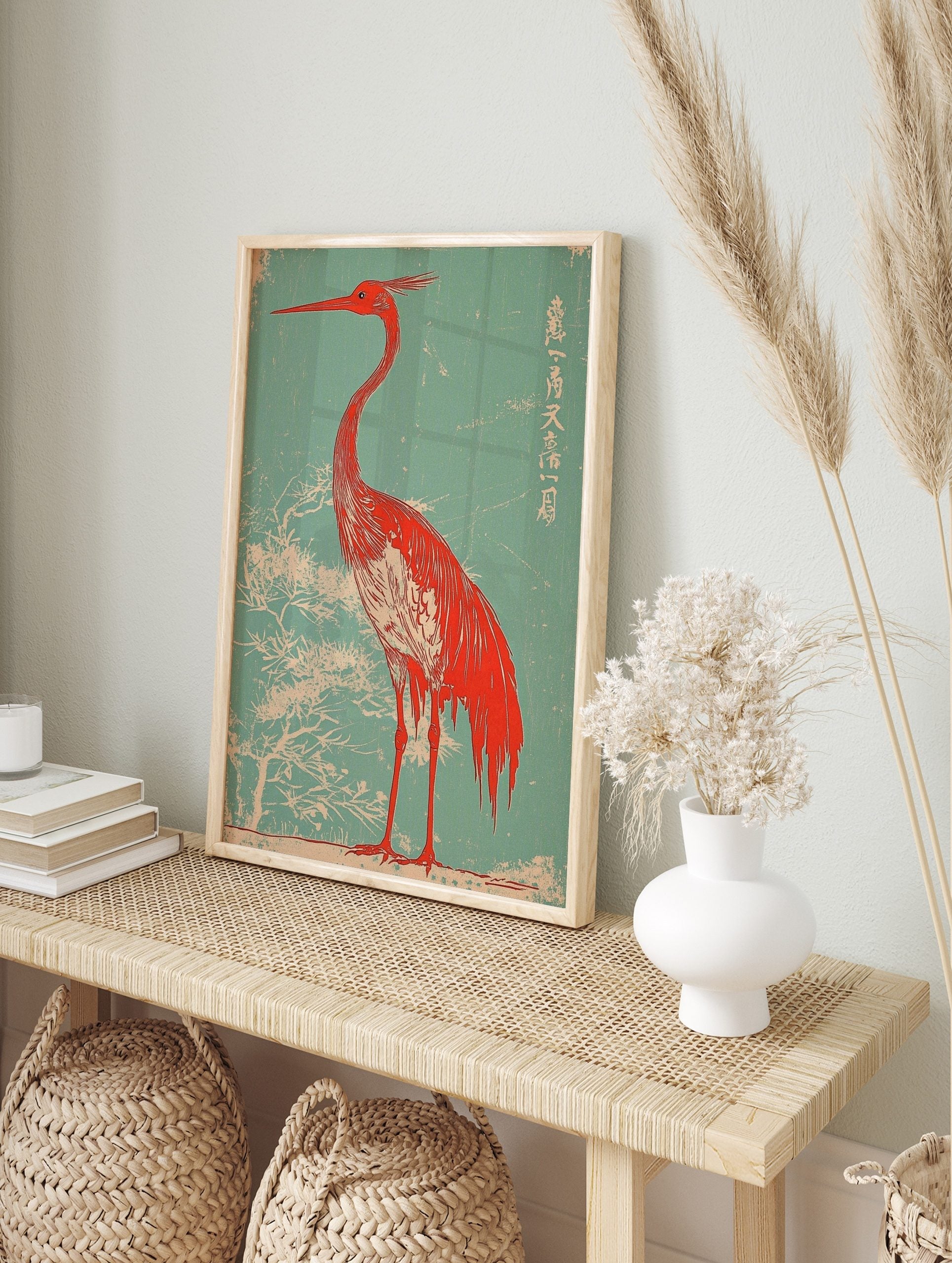 Red heron with long beak and crest, against a teal background with white tree branches and, in an alternate framed mockup