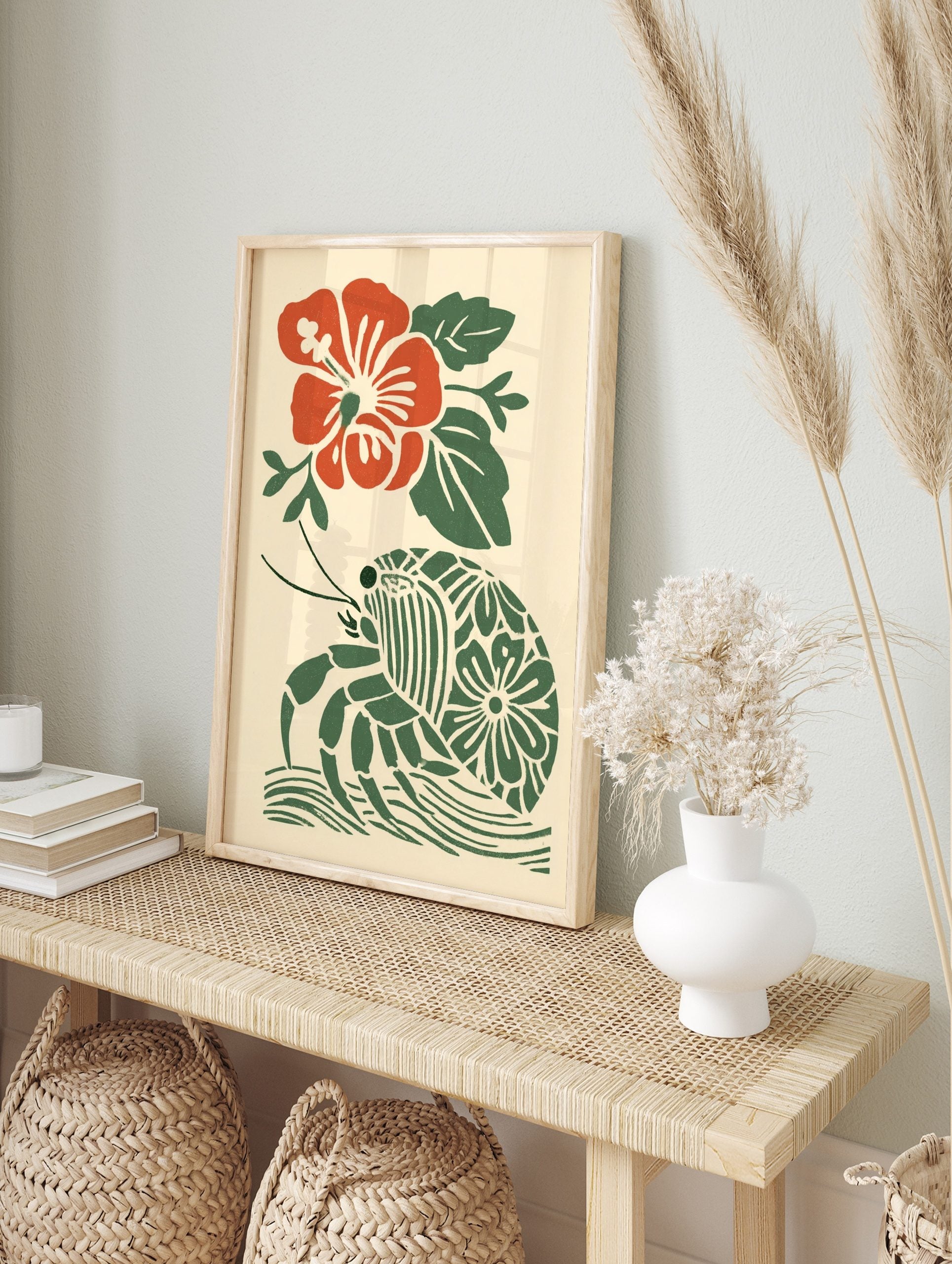 Red hibiscus flower and green hermit crab with patterned shell in a tropical block print style, in an alternate framed mockup