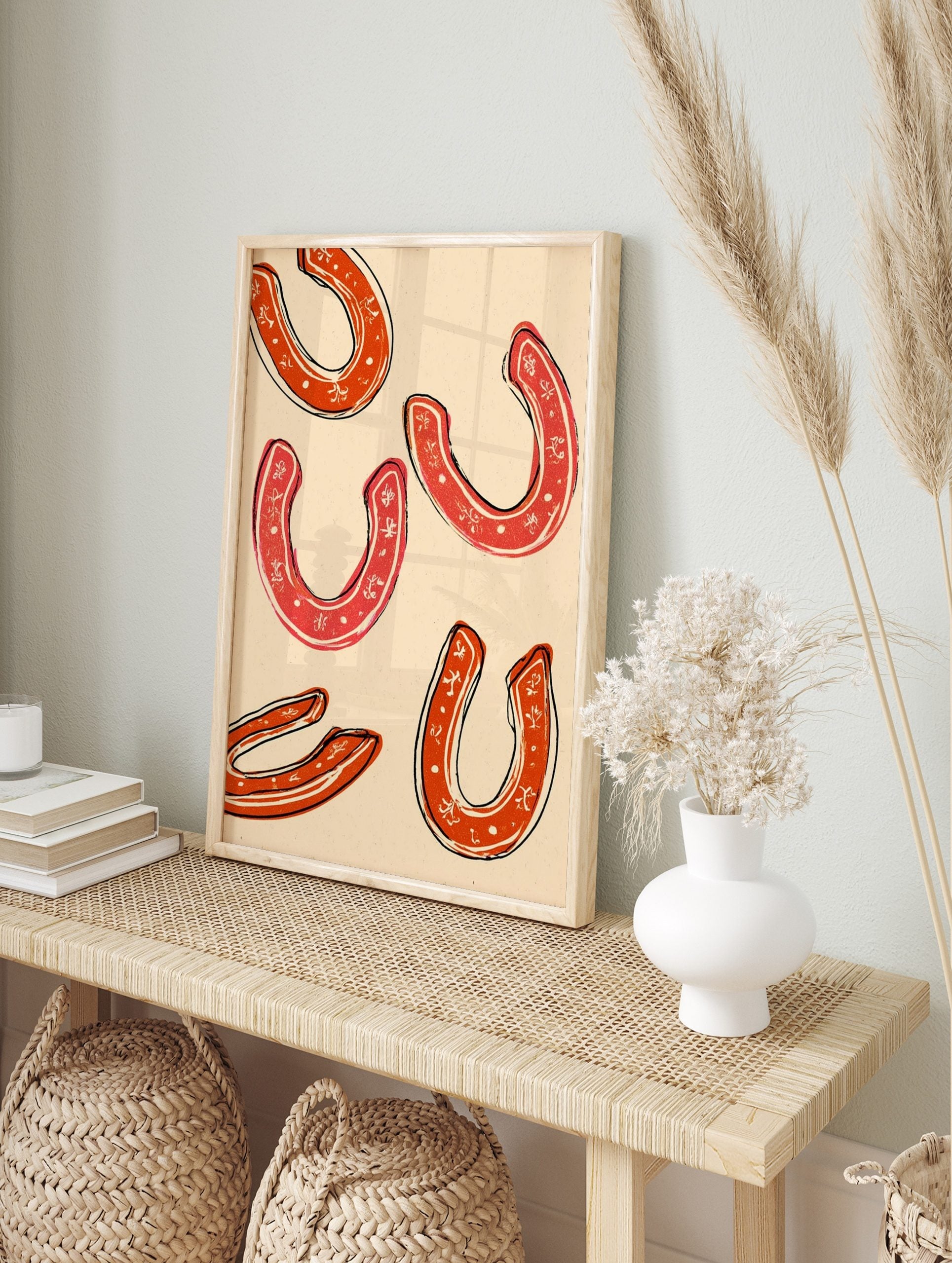 Five red horseshoes with white decorative patterns and black outlines on a cream background, in an alternate framed mockup