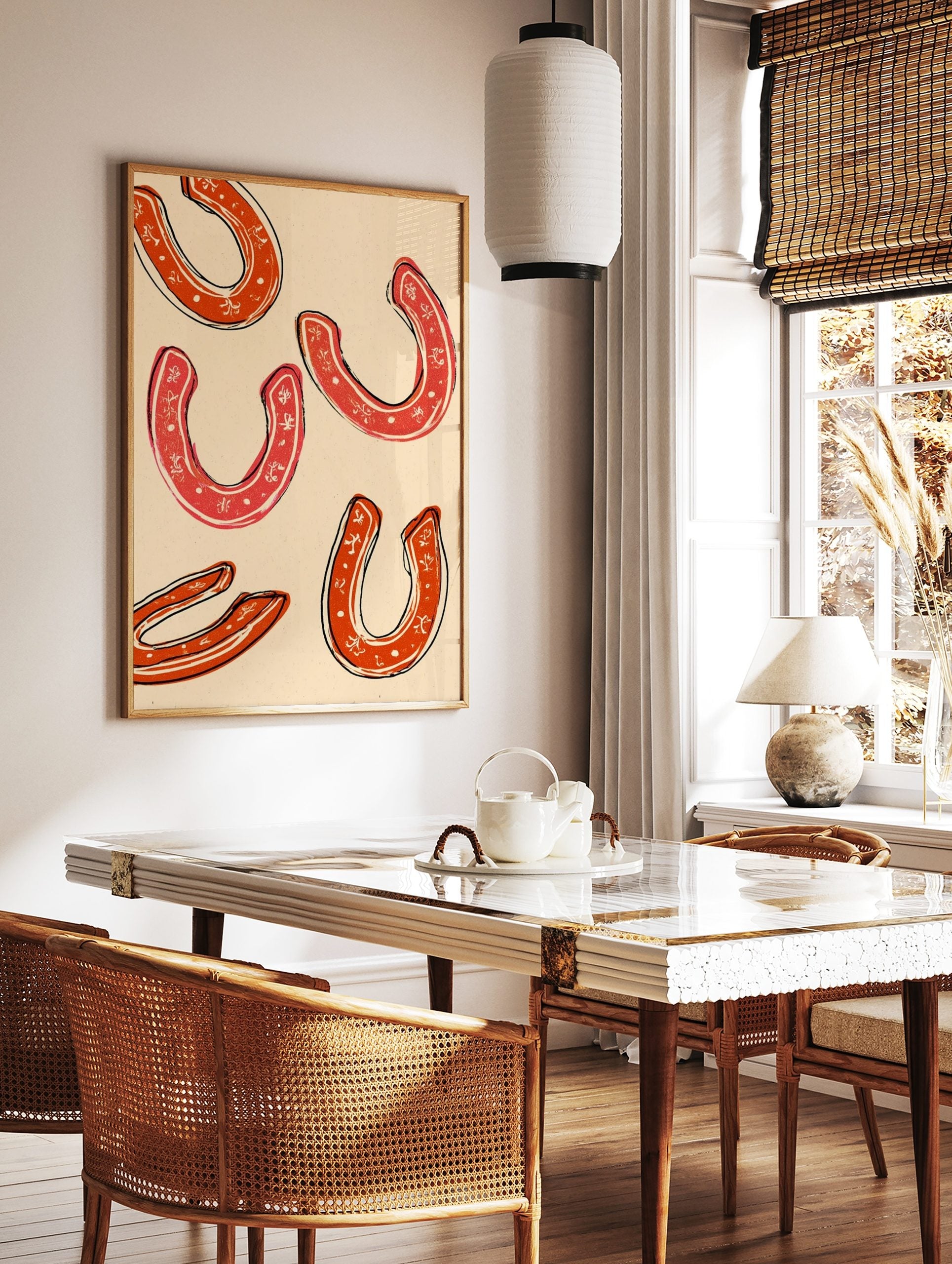 Five red horseshoes with white decorative patterns and black outlines on a cream background, in an, in a styled room mockup