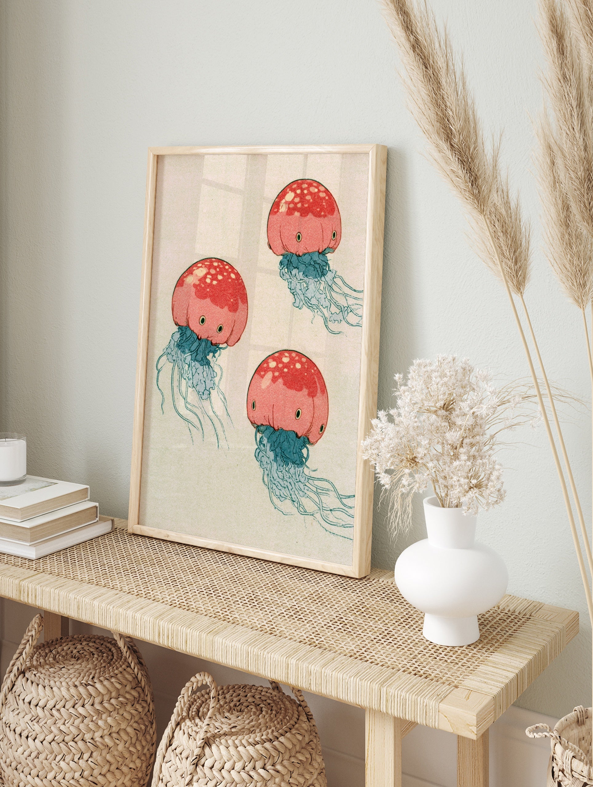 Illustrative red jellyfish wall art print with blue tentacles on a neutral background, in an alternate framed mockup