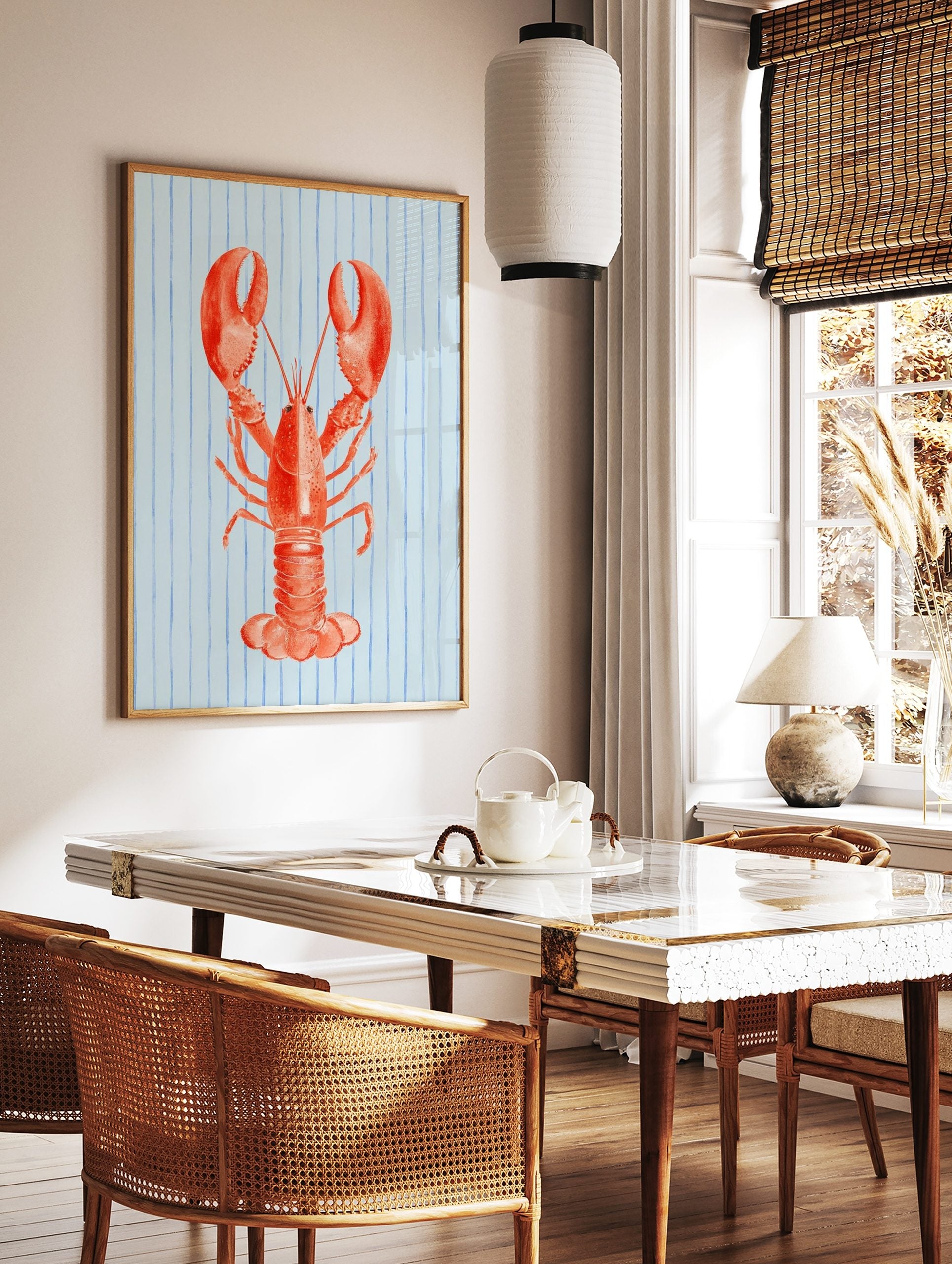 Illustrative red lobster wall art print on a light blue background with vertical blue stripes, in a styled room mockup