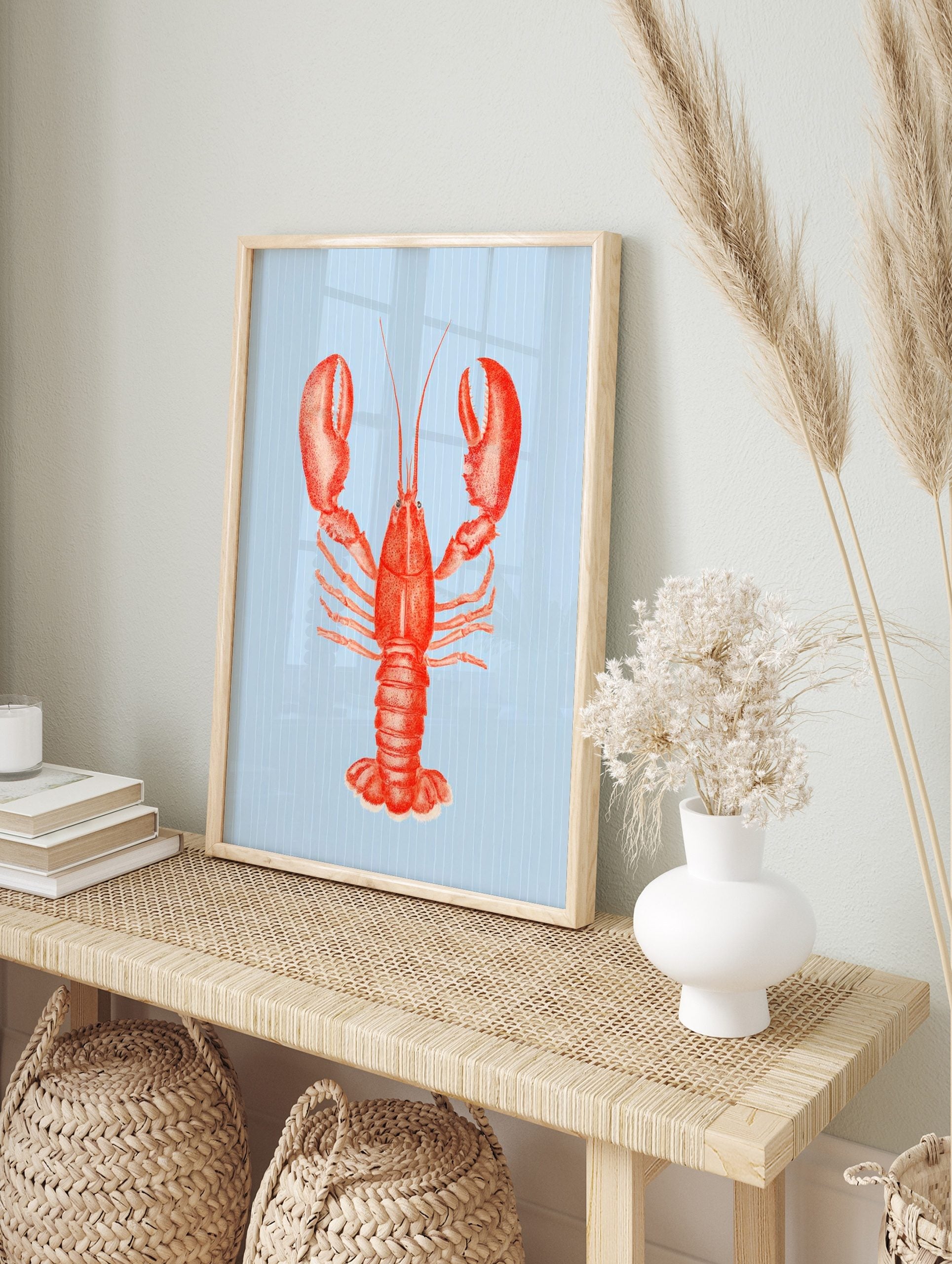 Red lobster illustration art print with large claws on a light blue striped background in, in an alternate framed mockup