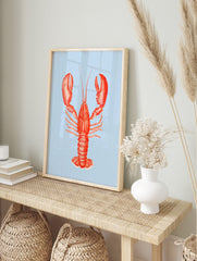 Red lobster illustration art print with large claws on a light blue striped background in, in an alternate framed mockup