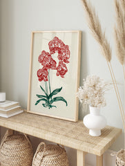 Red orchid botanical illustration wall art print with green leaves on a cream background, in an alternate framed mockup