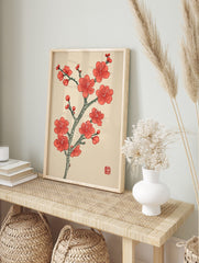 Red plum blossom branch with multiple flowers and buds, Japanese woodblock print style, in an alternate framed mockup