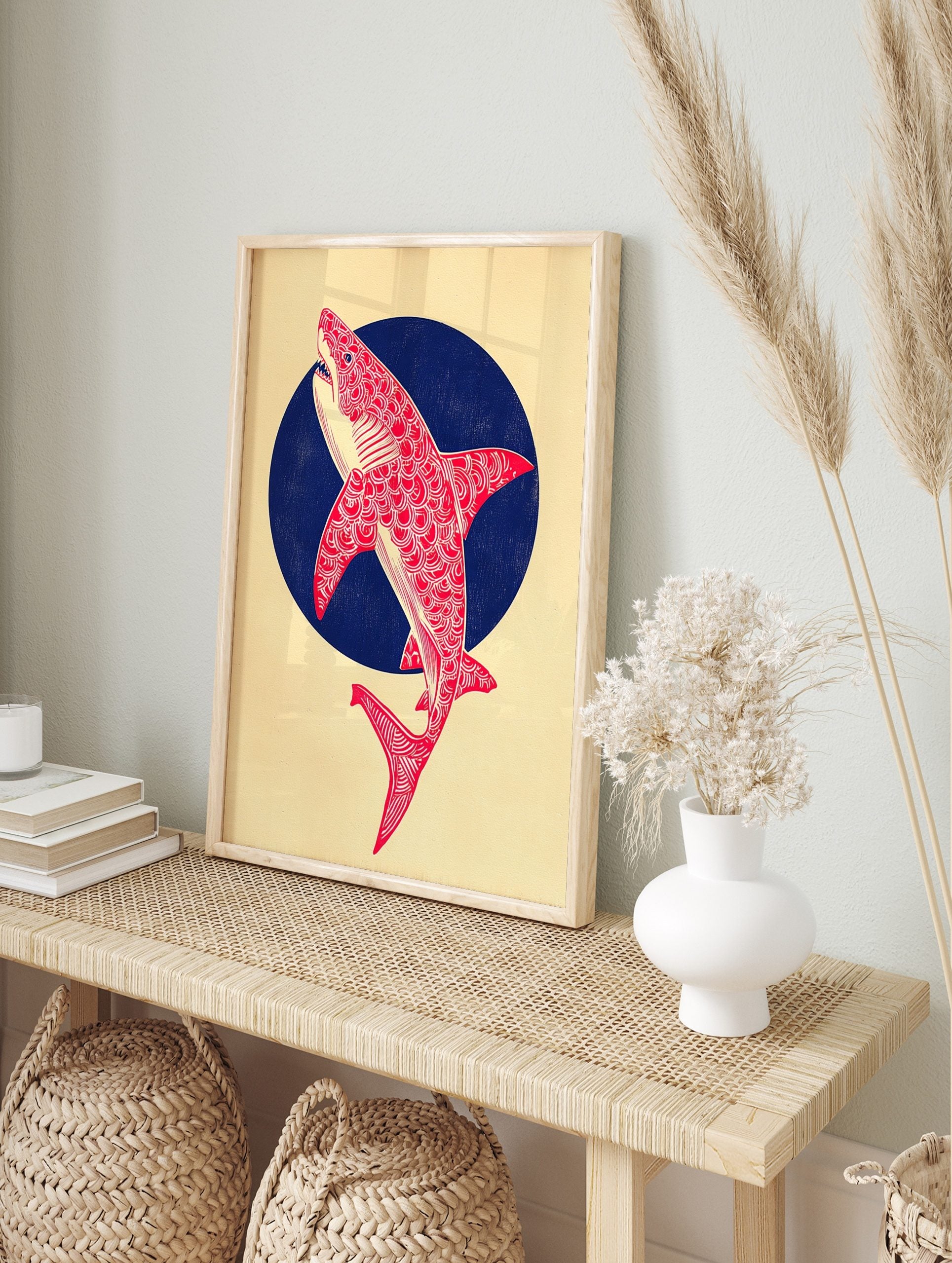 Red patterned shark illustration leaping from a dark blue circle on a cream background, in an alternate framed mockup