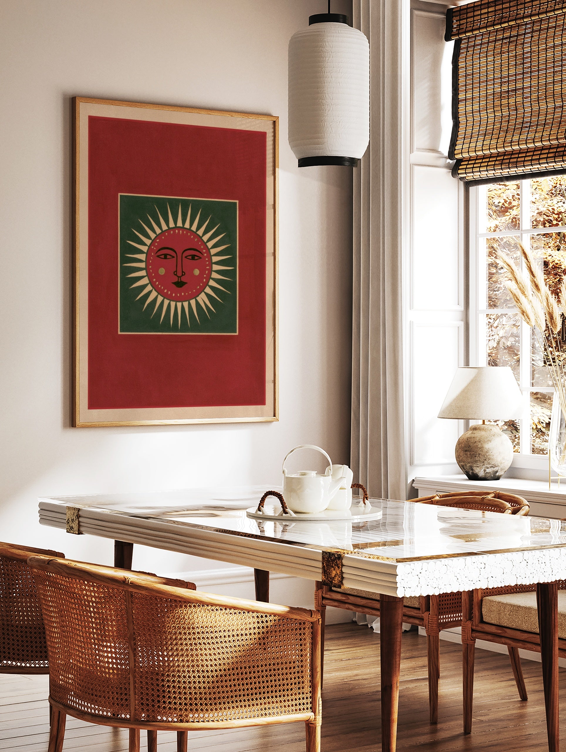 Stylized red sun face illustration with green background and cream rays, folk art style wall print, in a styled room mockup