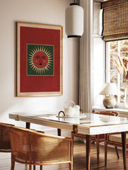 Stylized red sun face illustration with green background and cream rays, folk art style wall print, in a styled room mockup