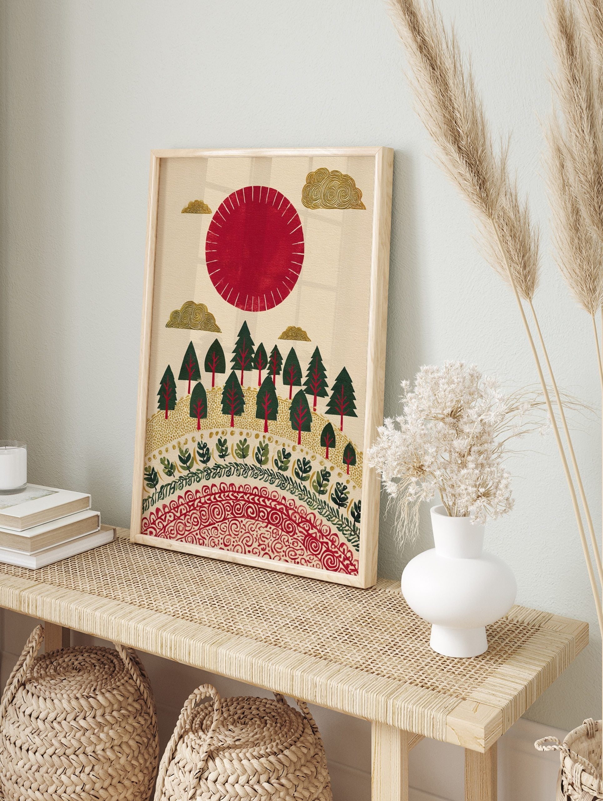 Illustrative red sun and golden clouds over a green forest with decorative patterns on a, in an alternate framed mockup