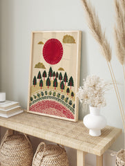 Illustrative red sun and golden clouds over a green forest with decorative patterns on a, in an alternate framed mockup