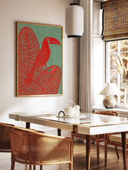 Red toucan with large bill perched on a striped tropical leaf against a textured teal background in, in a styled room mockup