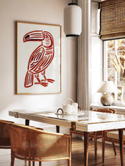 Red toucan illustration print with bold brushstrokes and dark accents on a white background, in a styled room mockup