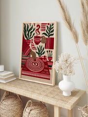 Illustrative red wall art print featuring a turntable, coffee cup, and potted plants on a, in an alternate framed mockup
