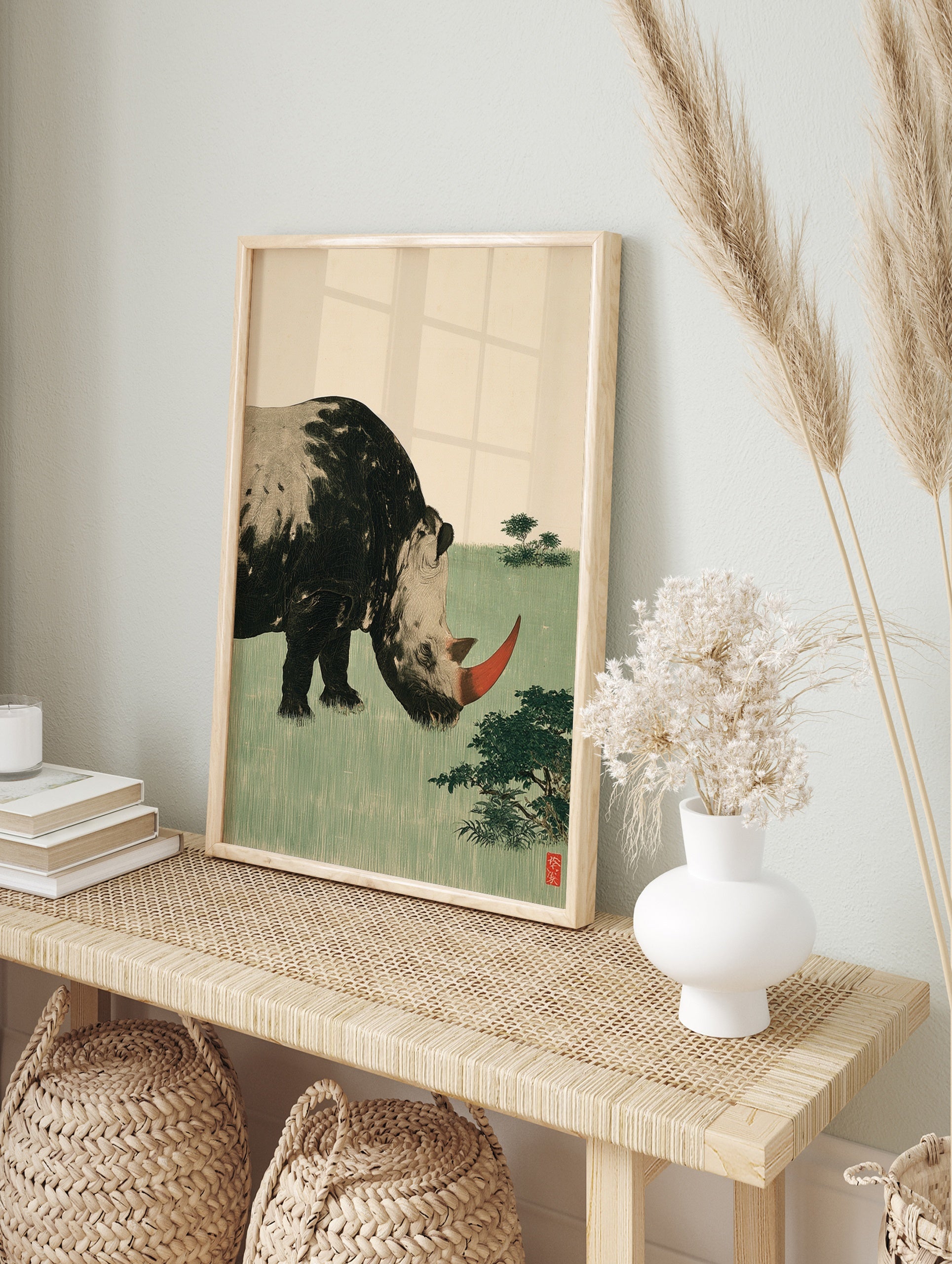 Stylized rhinoceros illustration with red horn and green field background art print, in an alternate framed mockup