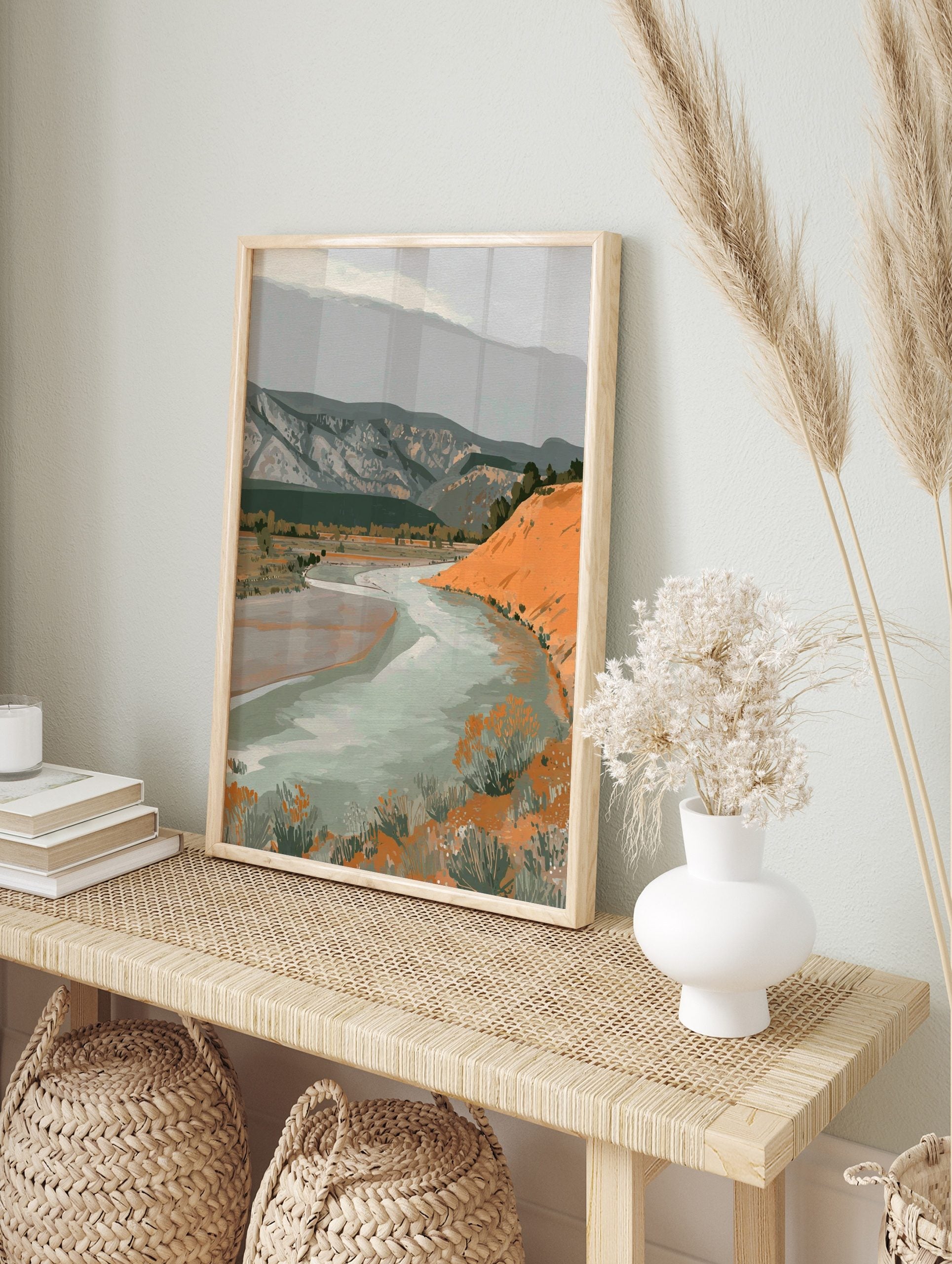 Illustrative landscape art print with a winding river, orange hill, and grey mountains under, in an alternate framed mockup