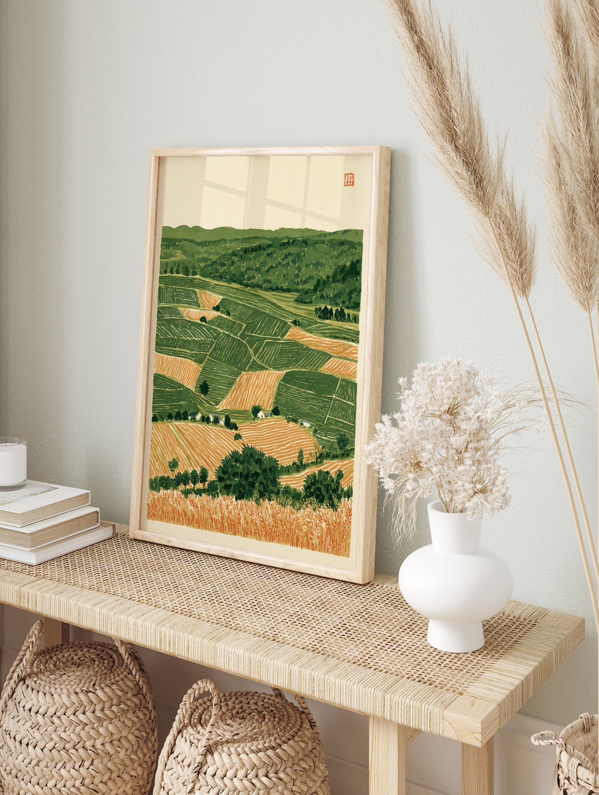 Rolling countryside landscape with patchwork fields, green hills, and foreground wheat, in an alternate framed mockup
