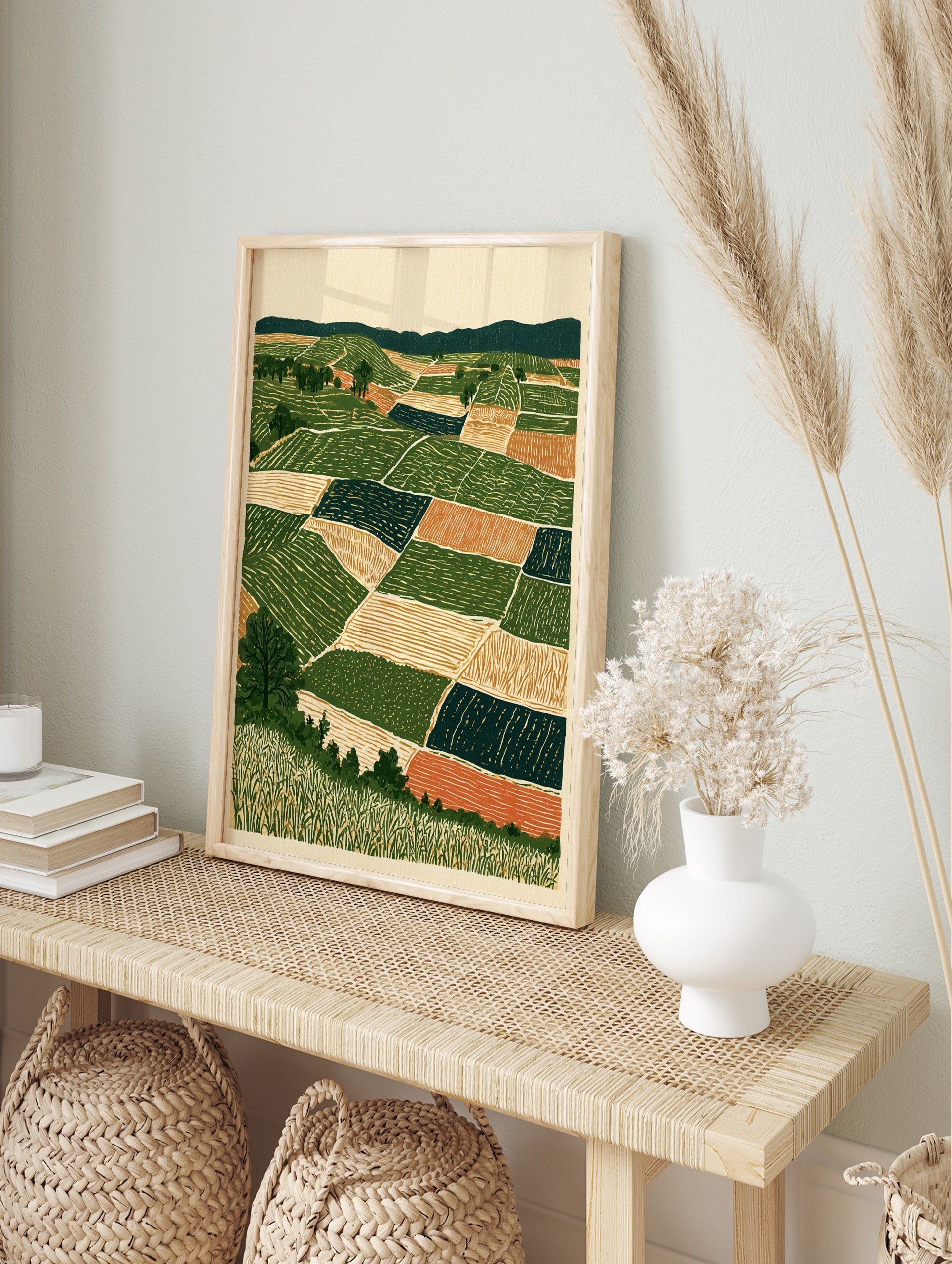 Stylised landscape art print showing geometric farm fields, rolling hills, and trees in, in an alternate framed mockup