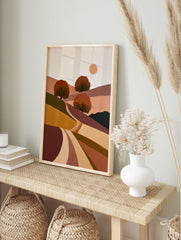 Minimalist landscape art print with rolling hills, three stylized trees, and a sun in earthy, in an alternate framed mockup