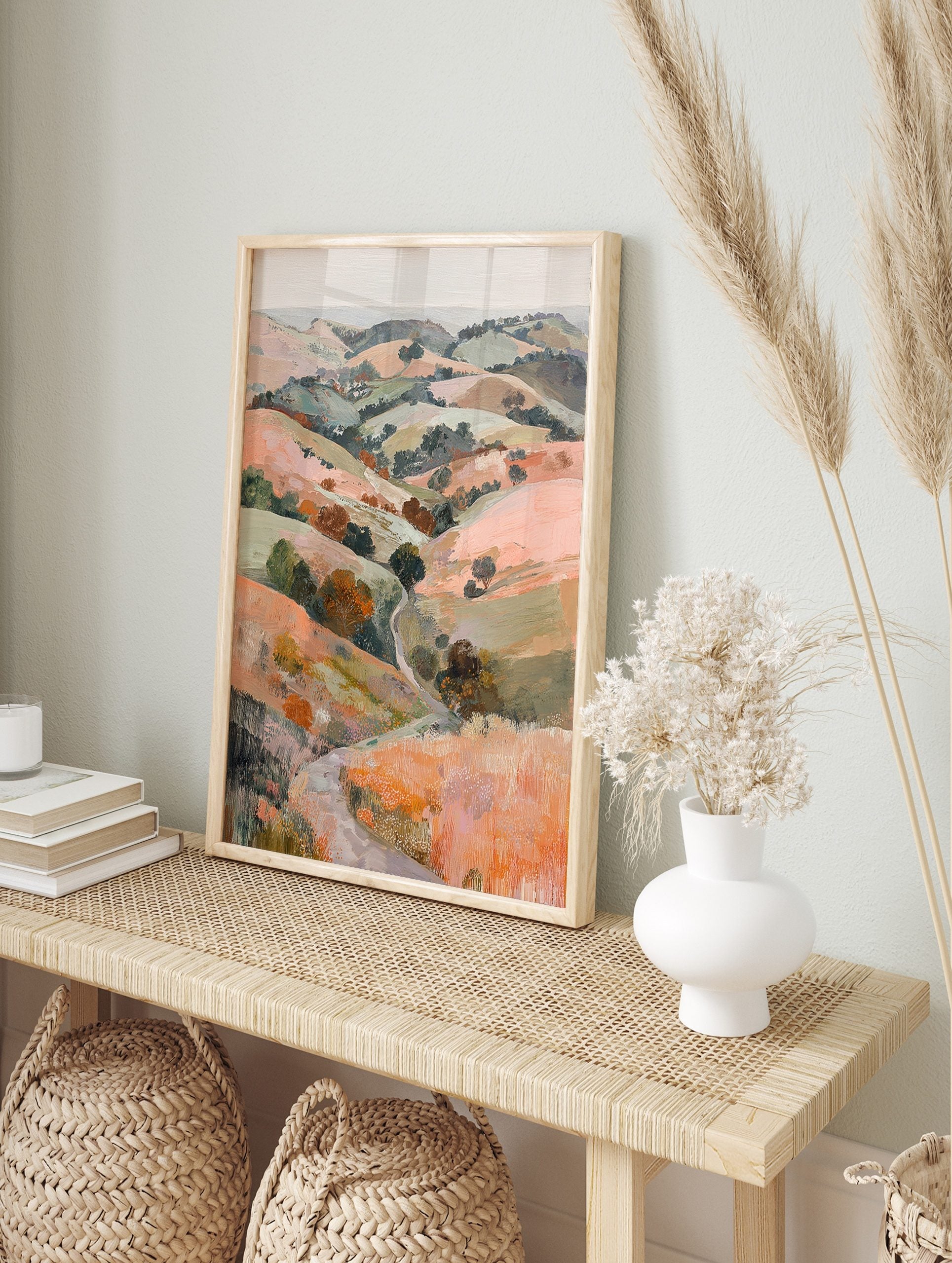 Painterly landscape print of rolling hills with a winding path and trees in peach, green, and, in an alternate framed mockup