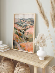 Painterly landscape print of rolling hills with a winding path and trees in peach, green, and, in an alternate framed mockup