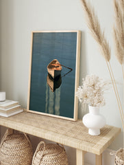 A wooden rowing boat floating on calm blue water with a detailed reflection, presented as a, in an alternate framed mockup