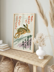 Running brown and tan hare illustration with red and black Japanese calligraphy on a white, in an alternate framed mockup