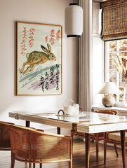 Running brown and tan hare illustration with red and black Japanese calligraphy on a white, in a styled room mockup