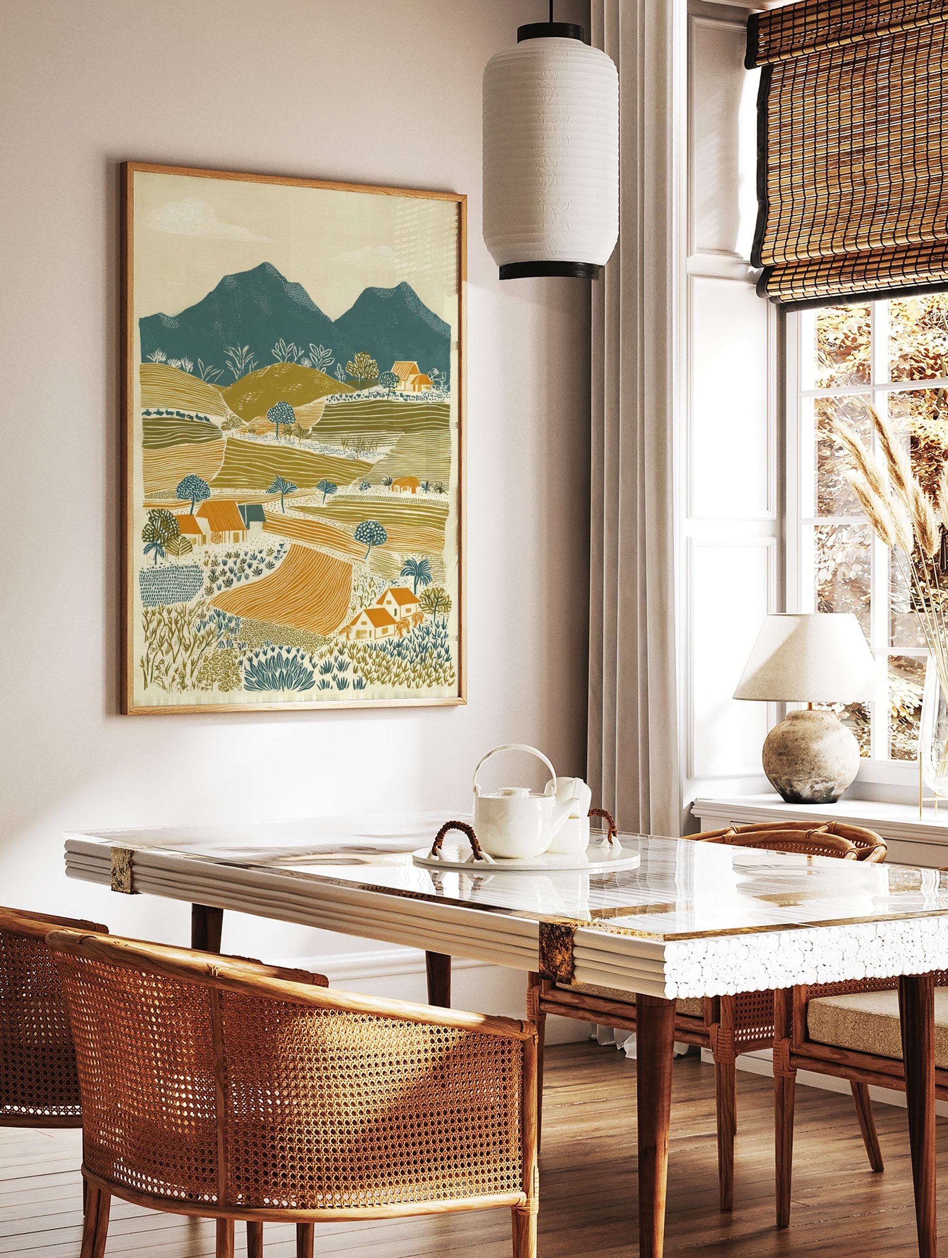 Illustrative rural landscape print with teal mountains, olive green hills, orange fields, and small, in a styled room mockup