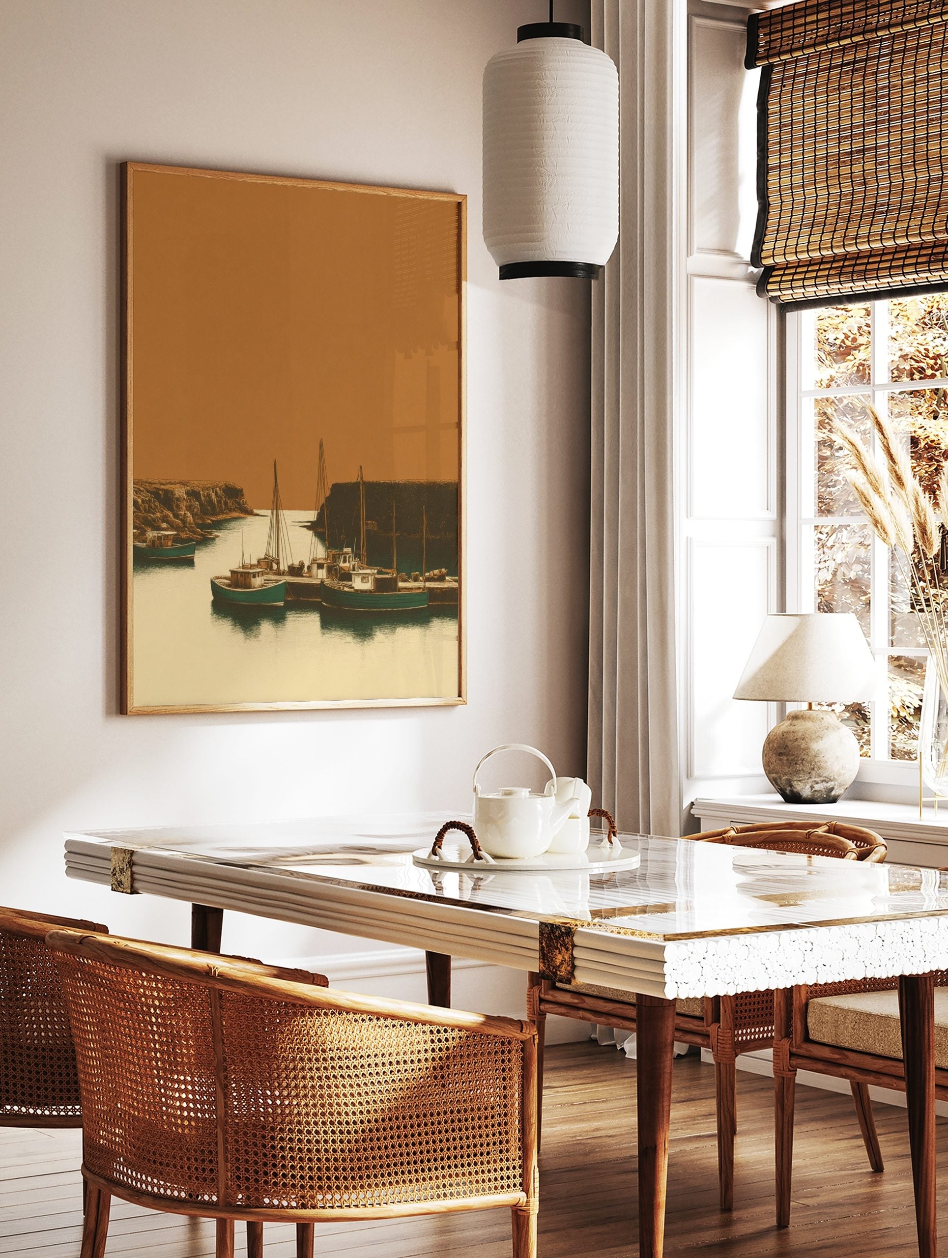 Illustrative print of fishing boats in a rustic harbour, flanked by rocky cliffs under an orange sky, in a styled room mockup