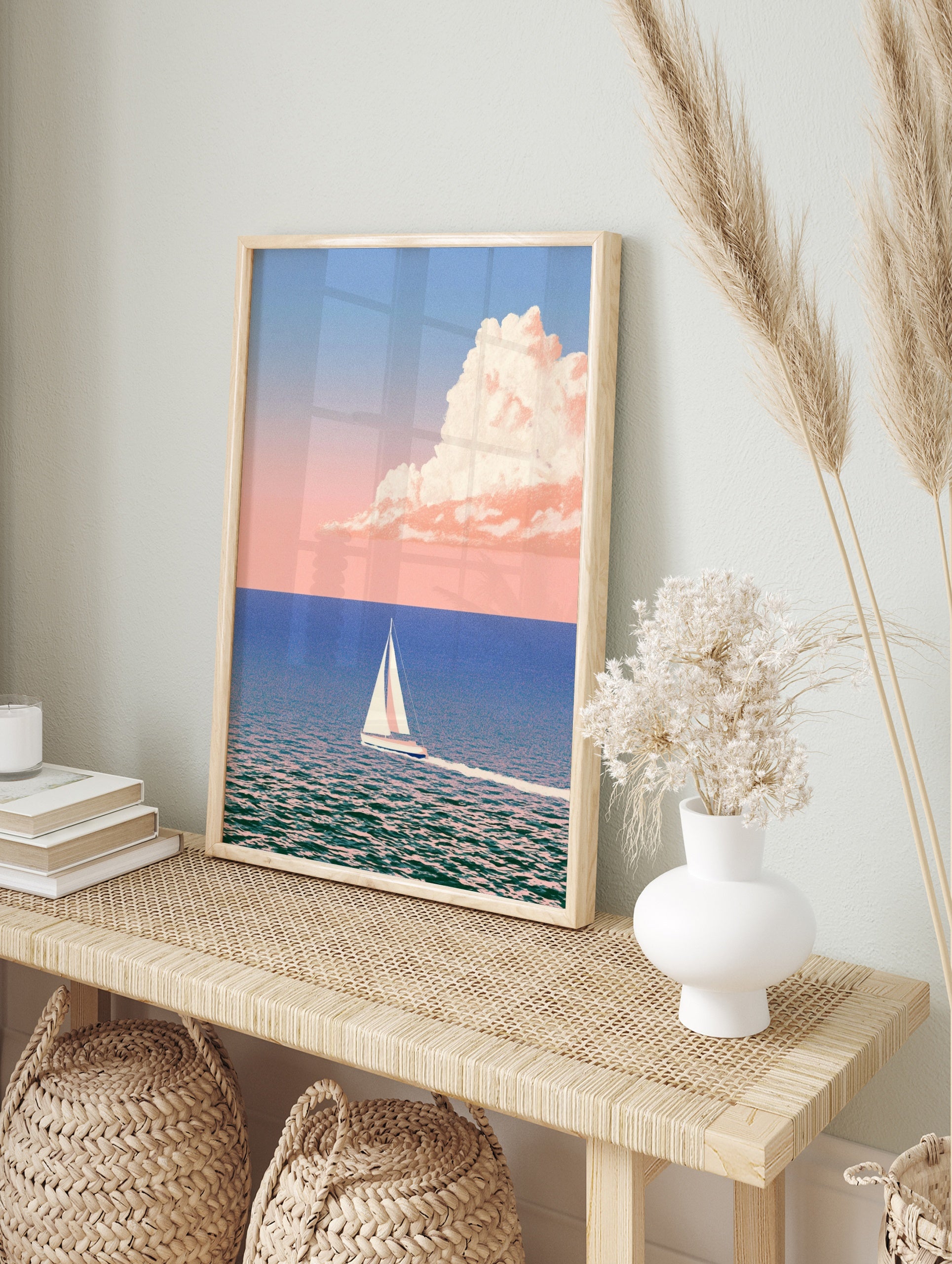 Minimalist sailboat art print on calm blue sea with pastel pink cloud in the sky, in an alternate framed mockup