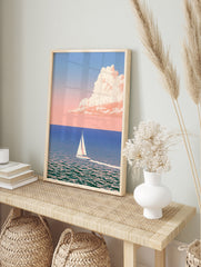 Minimalist sailboat art print on calm blue sea with pastel pink cloud in the sky, in an alternate framed mockup