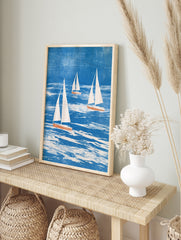 Three sailboats with white sails and coral hulls on a textured blue sea, illustrative, in an alternate framed mockup
