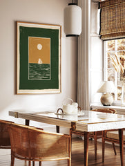 Minimalist sailboat wall art illustration with a green sea, tan sky, and white sun, in a graphic, in a styled room mockup