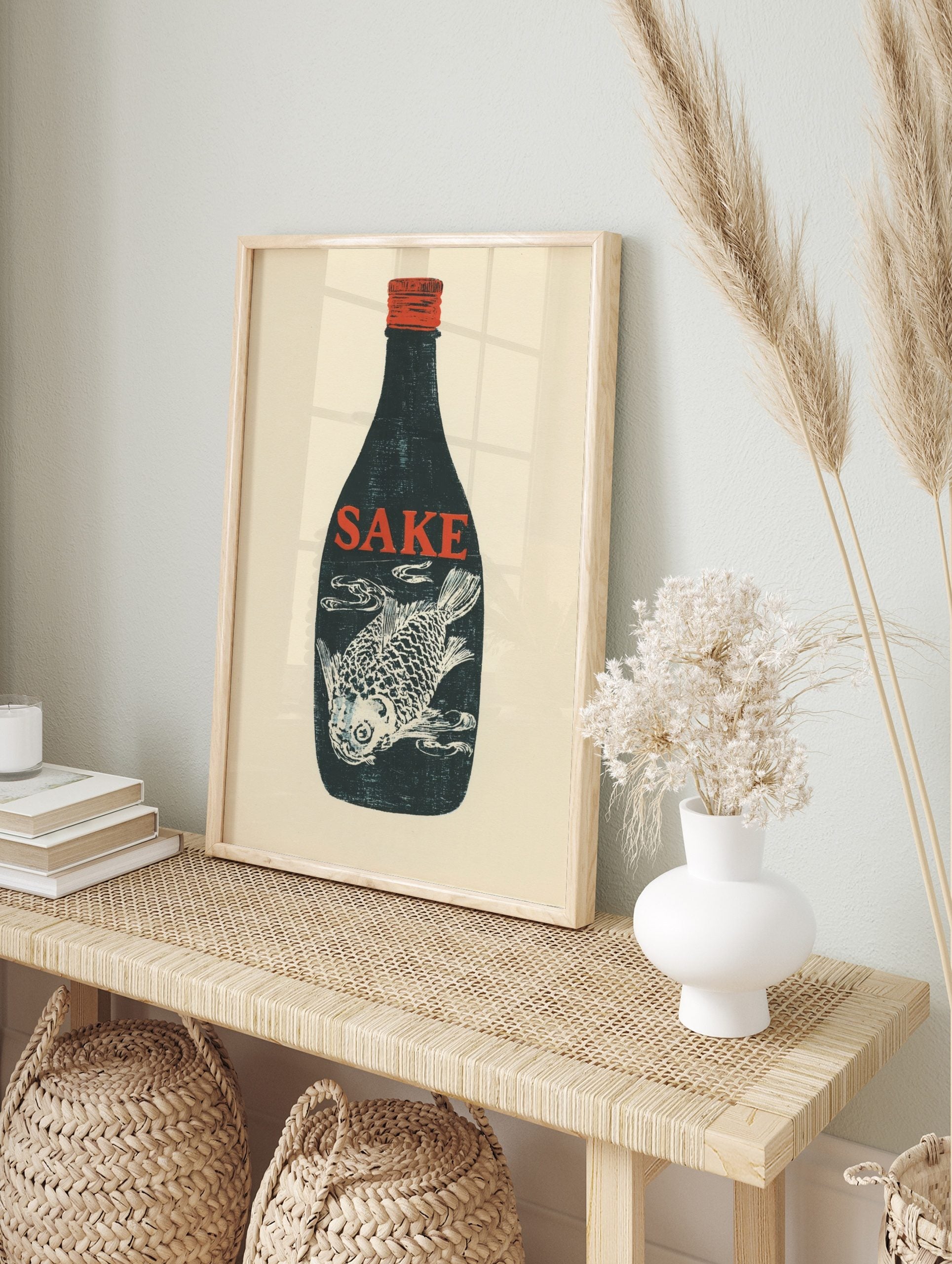 Dark blue sake bottle with red 'SAKE' text and white fish illustration inside, red cap, cream, in an alternate framed mockup
